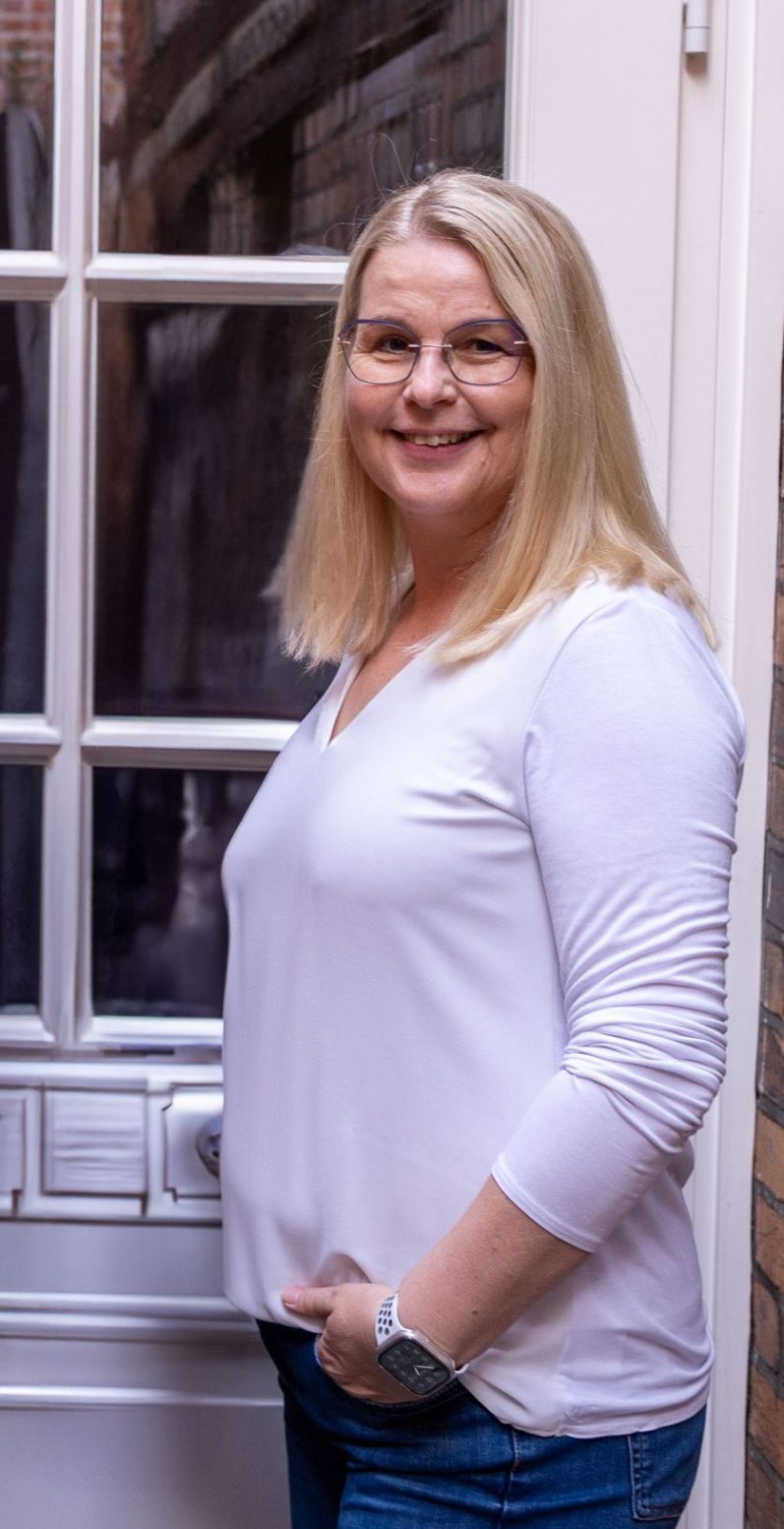 Fotografie von Sandra Brüchmann. Blonde Frau mit Brille lächelt in die Kamera